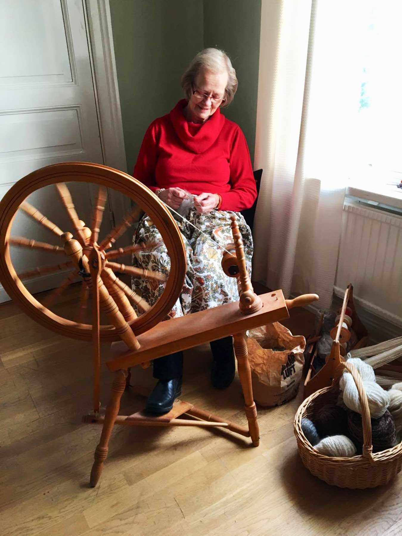 Bild på Anita Jansson som sitter spinner garn på Olofsborg.