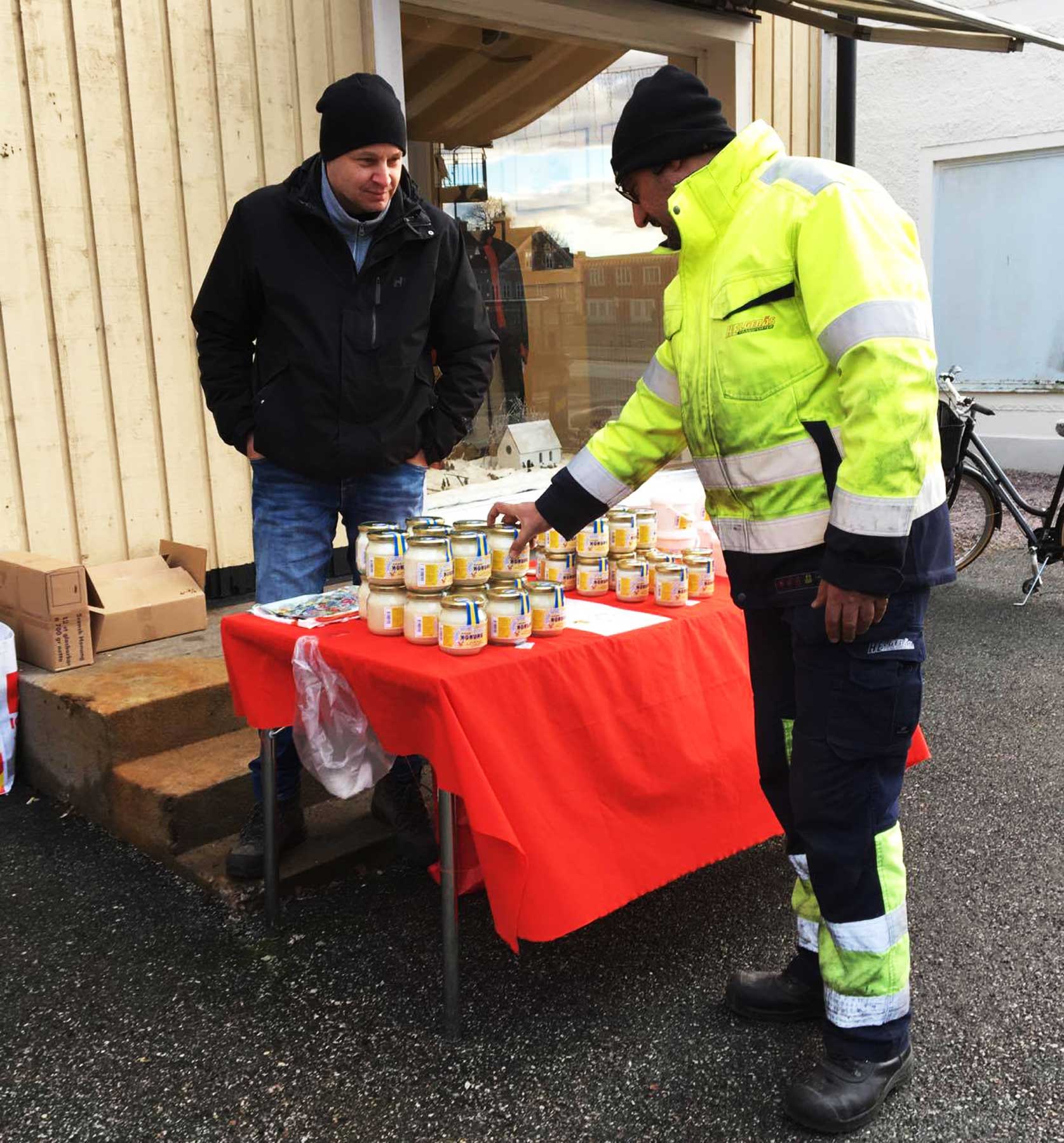 Bild på Lars-Åke Mårtensson som står med ett bord utanför Sockenstugan där han säljer sin Fellingsbro-honung.